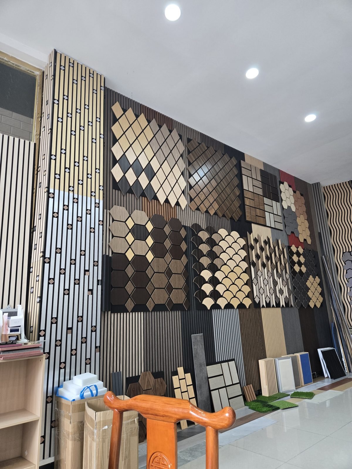 A showroom wall covered in slatted acoustic wall panels and patterned acoustic tiles in oak, walnut, black, gold and silver finishes