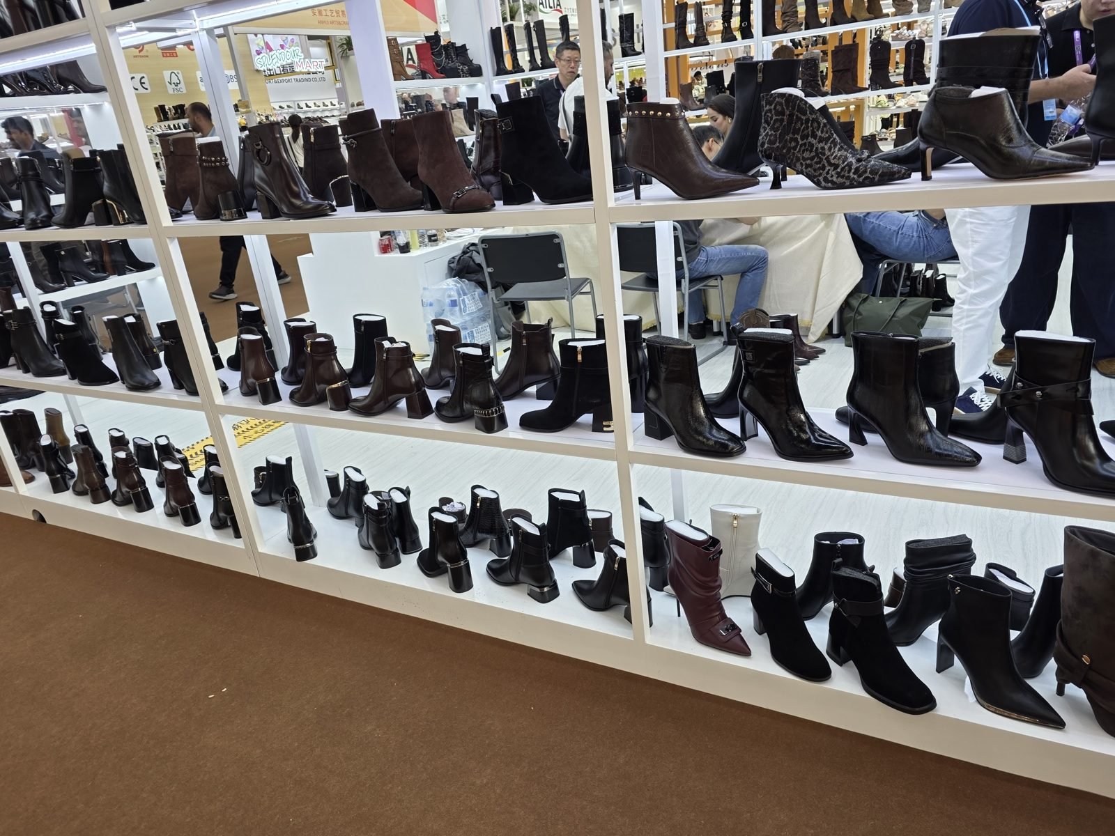 Shelves of women's ankle boots and heeled boots at a footwear exhibitor booth at the Canton Fair