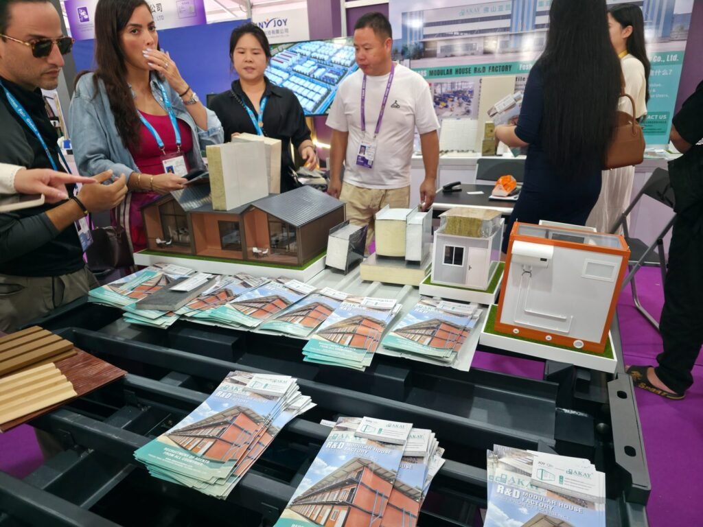 Buyers looking at modular house models, insulated wall panel samples and brochures at a Canton Fair booth