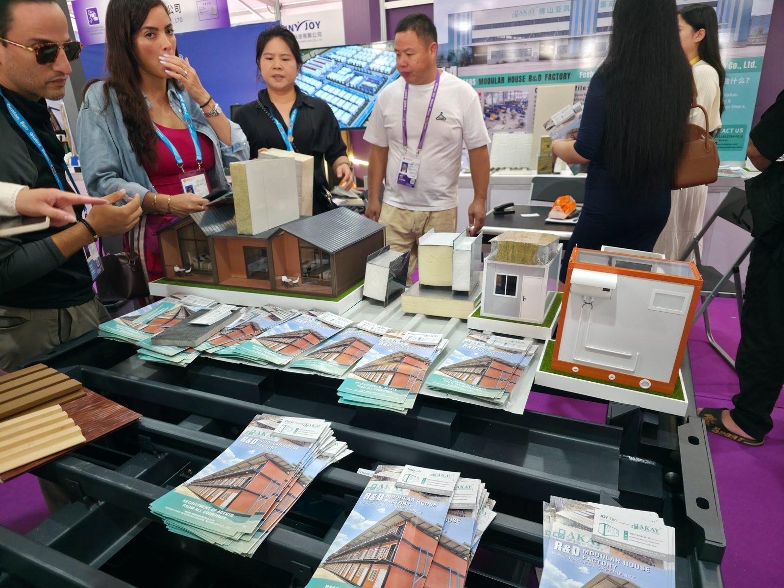 Buyers looking at modular house models, insulated wall panel samples and brochures at a Canton Fair booth